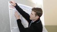 A man hangs up a poster.